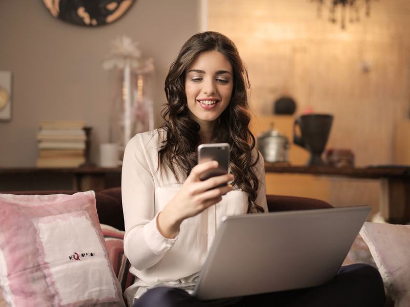 A traveller smiling at her phone at home